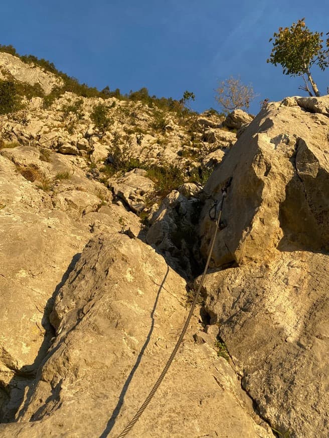 Stahlseil eines Klettersteigs an sonnigem Kalkfels
