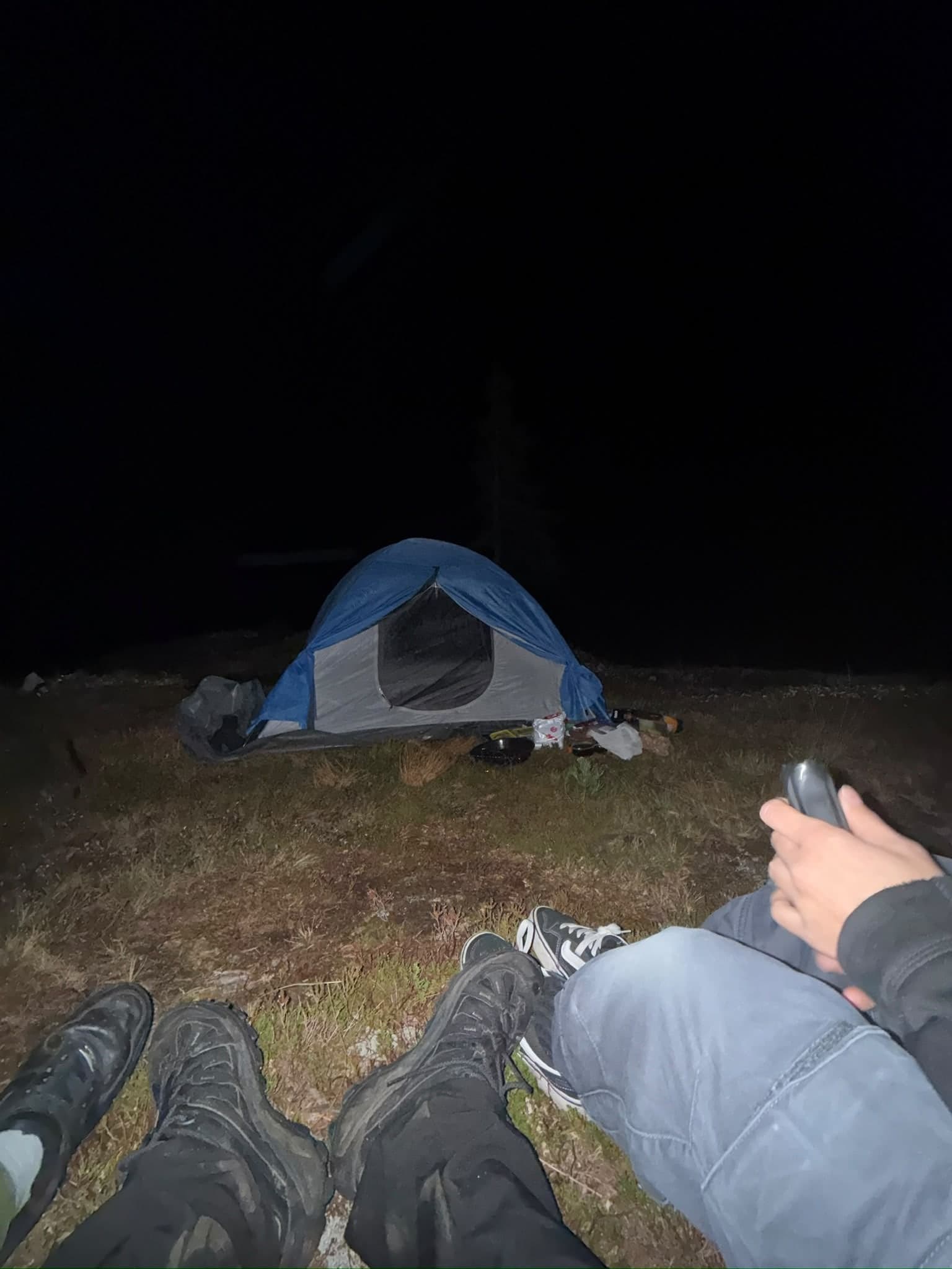 Blick über die eigenen Beine auf ein Zelt in der Nacht